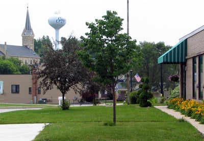 Downtown Slinger image with view of water tower, green grass and trees and U.S. flag flying